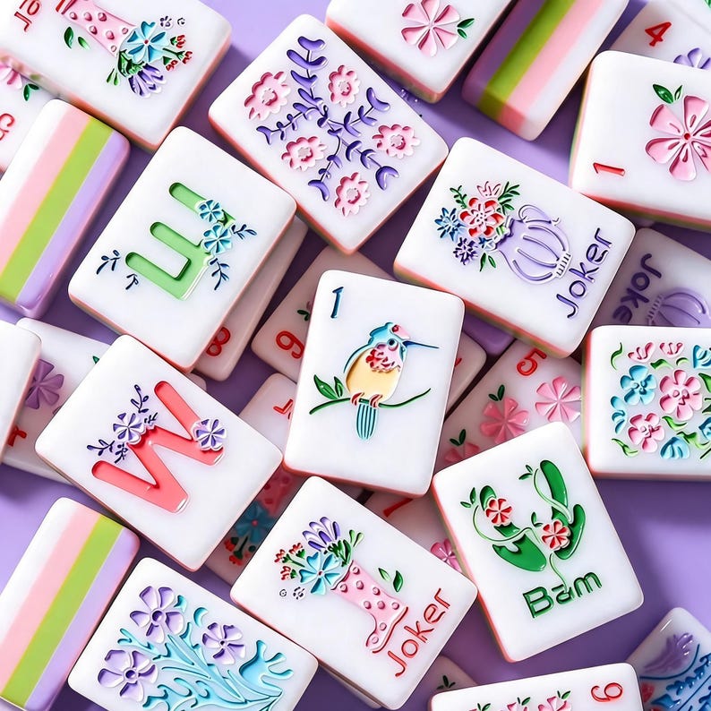 May include: A collection of white rectangular mahjong tiles featuring colorful engraved designs including floral arrangements, a bird on a branch, the letters W and U, the word Joker, the word Bam, and striped patterns in pink, green, and white.