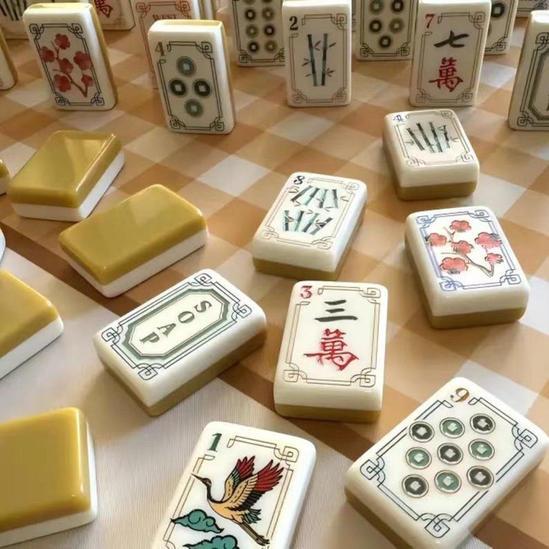 May include: A collection of rectangular tiles resembling mahjong pieces, featuring various designs including red floral patterns, green bamboo stalks, Chinese characters, a crane illustration, and one tile clearly labeled with the word SOAP.