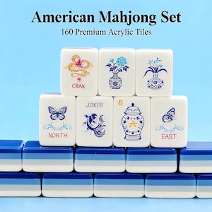 May include: An American Mahjong set featuring 160 premium acrylic tiles. The white tiles display blue, red, and yellow graphics including a dragon, flowers, a butterfly, a fish, and a vase. The tiles are stacked on blue, light blue, and white bases.