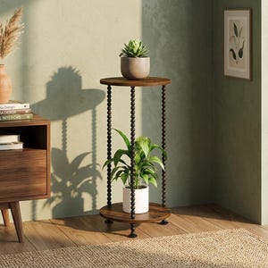 May include: A two-tier round side table with a dark wood finish and three vertical supports featuring a beaded design. The table has a small succulent in a gray pot on the top shelf and a green leafy plant in a white pot on the bottom shelf.