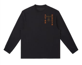 Puede incluir: Una camiseta negra de manga larga con cuello redondo y un gráfico en la parte superior izquierda del pecho. El gráfico muestra el contorno naranja de una figura estilo vitruviano flanqueado por el texto vertical naranja INTRA y SOMNIA en letra de bloque.