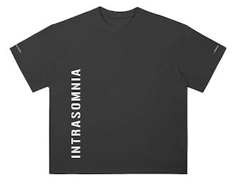 Puede incluir: Una camiseta de manga corta gris carbón con la palabra INTRASOMNIA impresa verticalmente en blanco en el lado izquierdo frontal. Las mangas también muestran un pequeño texto blanco en los bordes exteriores, incluyendo POTENTIAL.