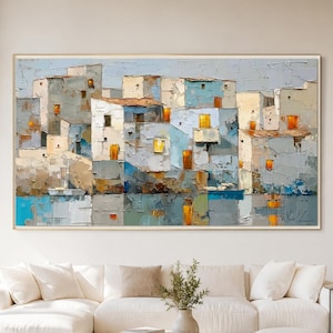 May include: A large rectangular oil painting featuring a textured, abstract coastal village scene with layered buildings in shades of blue, white, and beige, accented by bright orange windows, all reflected in the calm water below the structures.