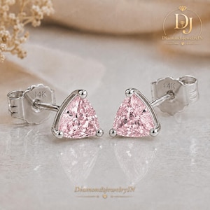 May include: A pair of stud earrings featuring trillion-cut light pink gemstones set in 14k white gold. Each earring has a secure post back stamped with 14K, showcasing a triangular faceted design that reflects light across the pale pink surfaces.