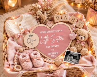 May include: A wicker gift basket containing a cream-coloured knit sweater, a heart-shaped sign reading "We are excited to say a little sister is on the way!", a wooden "Baby Olivia" disc, a teddy bear, pink booties, a sonogram, and baby blocks.