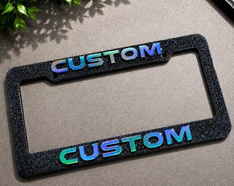 Cornice portatarga in acciaio inox con finitura glitter camaleontica e testo personalizzato in acrilico effetto specchio 3D.