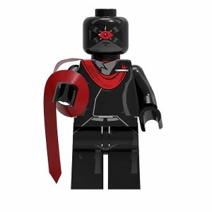 Puede incluir: Una minifigura de plástico negro con una cabeza que presenta un símbolo de ojo rojo y una máscara negra. El torso es negro con una bufanda roja sobre el pecho. Un accesorio largo y fino en forma de cinta roja está unido al brazo derecho.