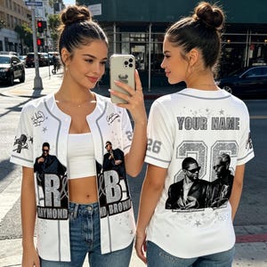 May include: A white baseball jersey featuring a graphic print of two men in sunglasses, the text R&B RAYMOND BROWN, and the number 26 on the back with the text YOUR NAME. The design includes silver glitter accents, stars, and grey trim details.