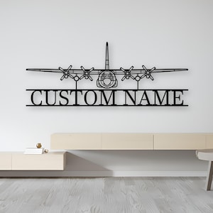 Könnte beinhalten: Ein schwarzes Wandkunstobjekt aus Metall, das die Silhouette eines viermotorigen Propellerflugzeugs über einer horizontalen Leiste zeigt, in die der Text CUSTOM NAME in einer fetten, serifenlosen Großbuchstabenschrift eingearbeitet ist.