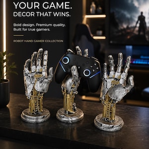 May include: Three silver and gold robotic hand sculptures designed as controller stands. The central hand holds a black wireless gaming controller with blue light accents. The text reads: ELEVATE YOUR GAME. DECOR THAT WINS. ROBOT HAND GAMER COLLECTION.