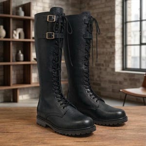 Puede incluir: Un par de botas negras hasta la rodilla con un acabado texturizado, cordones negros en la parte delantera y dos correas laterales ajustables con hebillas metálicas cerca de la parte superior. Las botas tienen punta redondeada y suela dentada.