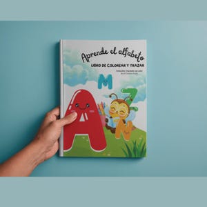 Puede incluir: Un libro de actividades de tapa blanda titulado Aprende el alfabeto LIBRO DE COLOREAR Y TRAZAR. La portada muestra una letra A grande roja, una M verde, una N amarilla y un personaje de abeja con gafas sobre un fondo de cielo azul.