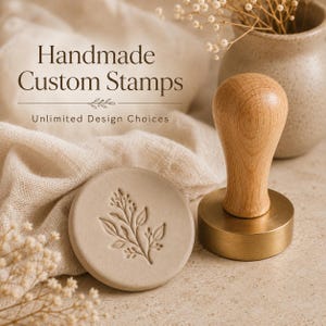 May include: A round wax seal stamp with a light wood handle and a brass base, positioned next to a circular clay disc featuring an embossed botanical leaf design. The text "Handmade Custom Stamps" and "Unlimited Design Choices" is visible.