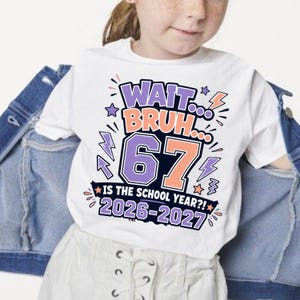 May include: A white t-shirt featuring a graphic design with the text "WAIT... BRUH... 67 IS THE SCHOOL YEAR?! 2026-2027". The design includes purple and orange lettering, lightning bolt icons, and stars, layered over a blue denim jacket.