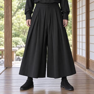 以下が含まれることがあります： ハイウエストでフロントに深い縦プリーツが入った、黒のワイドレッグパンツ。ゆったりとしたシルエットのパンツはふくらはぎの中間までの丈で、同色の黒い長袖シャツと黒いアンクルブーツを合わせています。