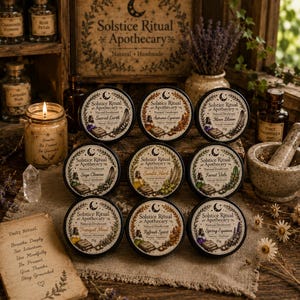 May include: Nine round black tins of Solstice Ritual Apothecary natural deodorant, each labelled with unique scent names like Sacred Earth and Moon Bloom, arranged in a grid on a textured cloth surface alongside a lit candle and apothecary jars.