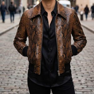 May include: A brown and black snakeskin-patterned leather jacket with a pointed collar, a silver-toned front zipper, and black ribbed cuffs and hem, worn over a solid black button-down shirt.