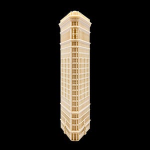 Può includere: Un modello architettonico color crema del Flatiron Building, caratterizzato da una pianta triangolare, più piani con motivi a finestra ripetuti, un cornicione dettagliato sulla sommità e una facciata stretta e appuntita.