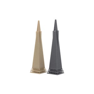 Pode incluir: Dois modelos de arranha-céus altos e esguios lado a lado. Um modelo é bege claro e o outro é cinza escuro. Ambos apresentam um design de torre pontiaguda e cônica com detalhes horizontais estriados e uma estrutura de base em treliça aberta.