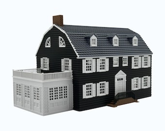 May include: A miniature model of a two-story house with black horizontal siding, a dark gray gambrel roof, and a brown chimney. The structure features white window frames, white shutters, a white front door with a small staircase, and a white side porch.