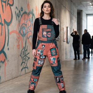 May include: A pair of color-blocked overalls featuring alternating panels of orange and dark teal leather. The garment is adorned with silver metal studs and multiple rectangular patches displaying graphic illustrations of eyes and faces.