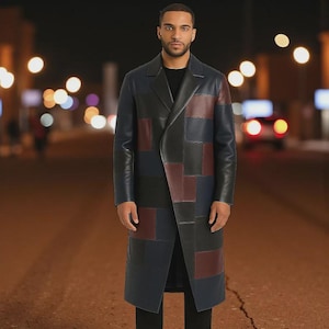 May include: A long, knee-length coat featuring a patchwork design of leather panels in shades of black, navy blue, and deep burgundy. The coat has a structured collar, long sleeves, and a clean, buttonless front closure, worn over a black shirt.