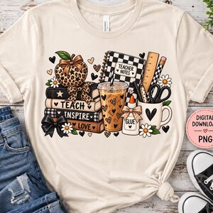 May include: A cream-coloured t-shirt featuring a graphic print of a stack of books labelled Teach, Inspire, Love, a leopard print apple, a checkered notebook labelled Teacher Notes, a coffee cup, a glue bottle, scissors, and a ruler.