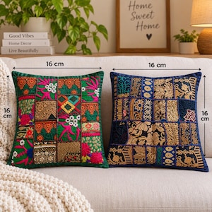 May include: Two square throw pillows measuring 16 cm by 16 cm. The left pillow features a green patchwork design with colorful floral and geometric embroidery. The right pillow displays a blue patchwork pattern with gold metallic thread embroidery.