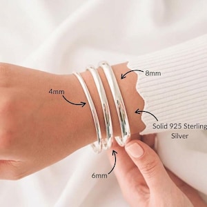 May include: Three solid 925 sterling silver bangles with smooth, rounded surfaces. The bracelets are labeled with widths of 4mm, 6mm, and 8mm, indicating the thickness of each individual piece of jewelry in this set of three silver bangles.