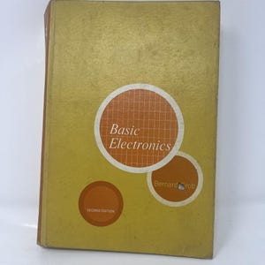 May include: A hardcover textbook titled Basic Electronics by Bernard Grob, Second Edition. The cover is mustard yellow with three orange circular graphics containing white grid patterns and text. The book has a brown spine and rectangular shape.