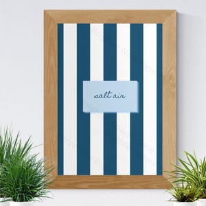 Peut inclure: Une impression d'art mural verticale encadrée présentant un motif de rayures verticales alternées bleu foncé et blanches. Au centre, un rectangle bleu clair contient le texte salt air écrit en écriture cursive bleu foncé.