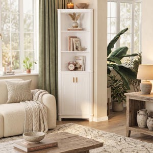 Puede incluir: Un armario esquinero blanco con tres estantes abiertos y una secci&oacute;n de almacenamiento inferior con dos puertas. El mueble presenta detalles estriados verticales en las puertas, peque&ntilde;os tiradores dorados y contiene libros y objetos decorativos.