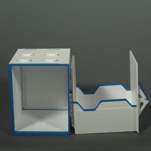 K&ouml;nnte beinhalten: Ein modularer Aufbewahrungsorganizer in Wei&szlig; und Blau, bestehend aus einer rechteckigen Box mit hohlem Innenraum und einer separaten, oben offenen Ablage mit eingekerbten Seitenw&auml;nden. Die Teile bestehen aus starren Platten mit blauem Rand.