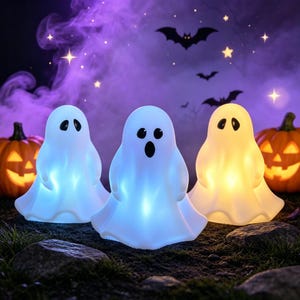 May include: Three illuminated ghost-shaped lamps with smooth white surfaces and black oval eyes and mouths. The central ghost glows with a cool blue light, while the flanking ghosts emit soft blue and warm yellow light, set against a dark background.