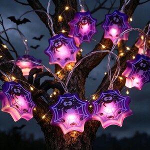 May include: A string of Halloween-themed LED lights featuring purple, star-shaped housings with white spiderweb patterns and black spider graphics. Each star-shaped light glows with a bright pinkish-purple illumination, connected by a thin, clear wire.
