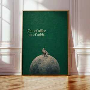 Könnte beinhalten: Ein rechteckiger Wandkunstdruck in einem goldenen Rahmen mit dunkelgrünem Hintergrund und dem Text "Out of office, out of orbit." Unter dem Text sitzt ein Astronaut auf einem Stuhl auf einer kraterreichen, grauen mondähnlichen Kugel.