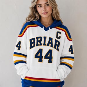 May include: A white hooded sweatshirt featuring blue, yellow, and red stripes on the sleeves and hem. The front displays the text BRIAR in large blue letters, the number 44, and a letter C, with the number 4 printed on each sleeve.
