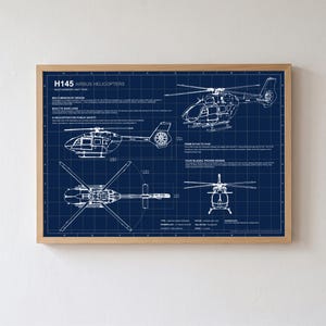 Op de afbeelding: Een ingelijste blauwdrukposter met technische lijntekeningen van de H145 Airbus-helikopter in wit op een donkerblauwe rasterachtergrond. De print toont meerdere aanzichten van het luchtvaartuig, waaronder zij-, boven- en vooraanzichten met tekst.
