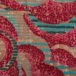 May include: A woven fabric featuring a textured pattern of large, swirling magenta shapes with a dotted surface. The background consists of horizontal stripes in alternating shades of teal and dark green set against a tan, neutral-colored base.