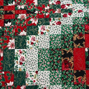 May include: A patchwork quilt featuring a repeating grid of rectangular fabric squares. The pattern displays festive holiday motifs including red poinsettias, green holly leaves with red berries, and gold filigree accents on white, red, and green backgrounds.