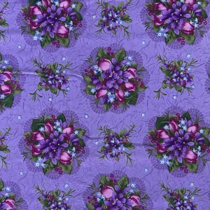 May include: A purple fabric featuring a repeating pattern of floral bouquets composed of dark purple tulips, small blue forget-me-nots, and green leaves. The background has a subtle, textured, marbled effect with faint, delicate lace-like circular motifs.
