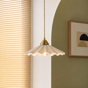 May include: A pendant light fixture featuring a white, scalloped ceramic shade with a fluted edge. The shade is suspended by a twisted gold-toned cord and attached to a tiered, metallic gold-toned cap that houses a single glowing light bulb.