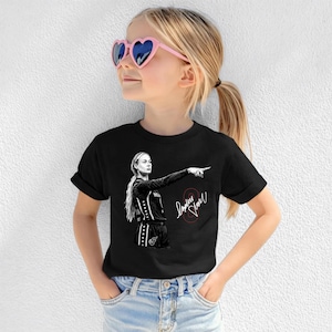 May include: A black short-sleeve t-shirt featuring a white graphic illustration of a basketball player pointing with one arm extended. The design includes a red number eight and a white signature. The shirt has a crew neckline and cuffed sleeves.