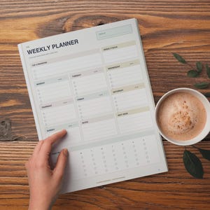 Può includere: Una pagina di pianificatore settimanale con sfondo grigio chiaro e testo nero. Il layout include sezioni per le priorità, programmi giornalieri dal lunedì alla domenica, un focus settimanale, note e una sezione per la prossima settimana.