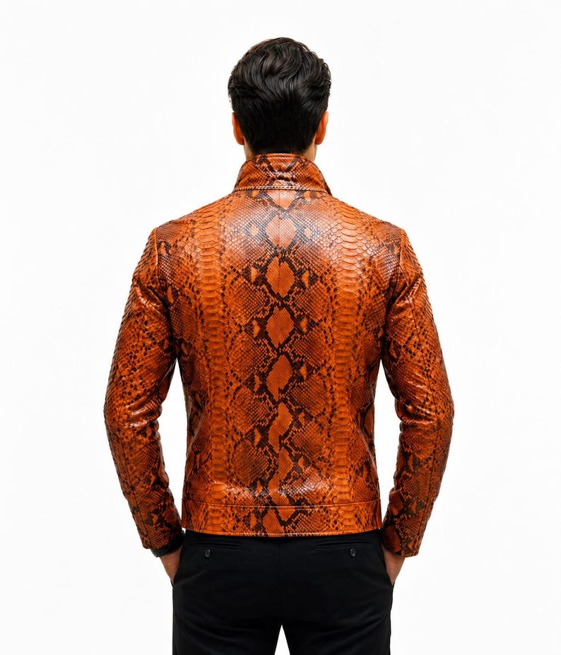 May include: A long-sleeved jacket featuring a vibrant orange and black snakeskin pattern. The garment has a high collar, a structured fit, and a full-length zipper closure, shown from the back view against a plain white background.