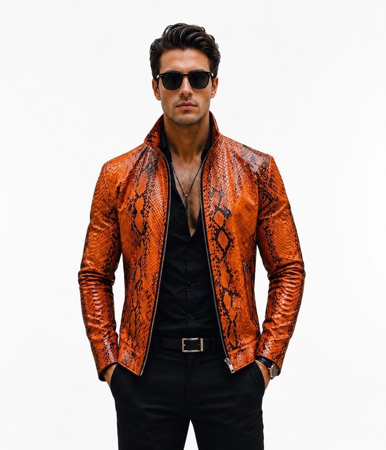 May include: A vibrant orange and black snakeskin-patterned leather jacket with a high collar and a full-length front zipper. The jacket is worn over a black button-down shirt and black trousers, paired with dark-tinted sunglasses and a silver necklace.