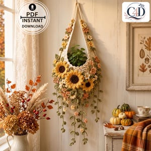 Könnte beinhalten: Ein cremefarbener gehäkelter Pflanzenhänger mit großen gelben Sonnenblumen, kleinen orangefarbenen und weißen Blüten sowie grünen Blättern. Das Design umfasst lange, herabhängende Ranken. Der Text im Bild lautet PDF INSTANT DOWNLOAD und C4D.