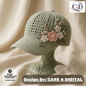 May include: A sage green crochet baseball cap featuring an open-weave grid pattern on the crown and a solid brim. The side is decorated with three-dimensional crocheted flowers in shades of dusty pink and cream, accented with small green leaves.