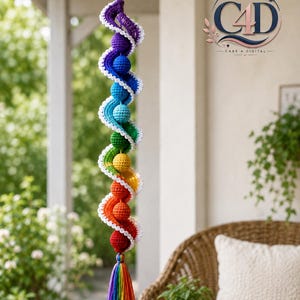 May include: A hanging crochet spiral ornament featuring a vertical sequence of spheres in rainbow colors, including purple, blue, green, yellow, orange, and red. A white crocheted border winds around the spheres, ending in a rainbow-colored tassel.