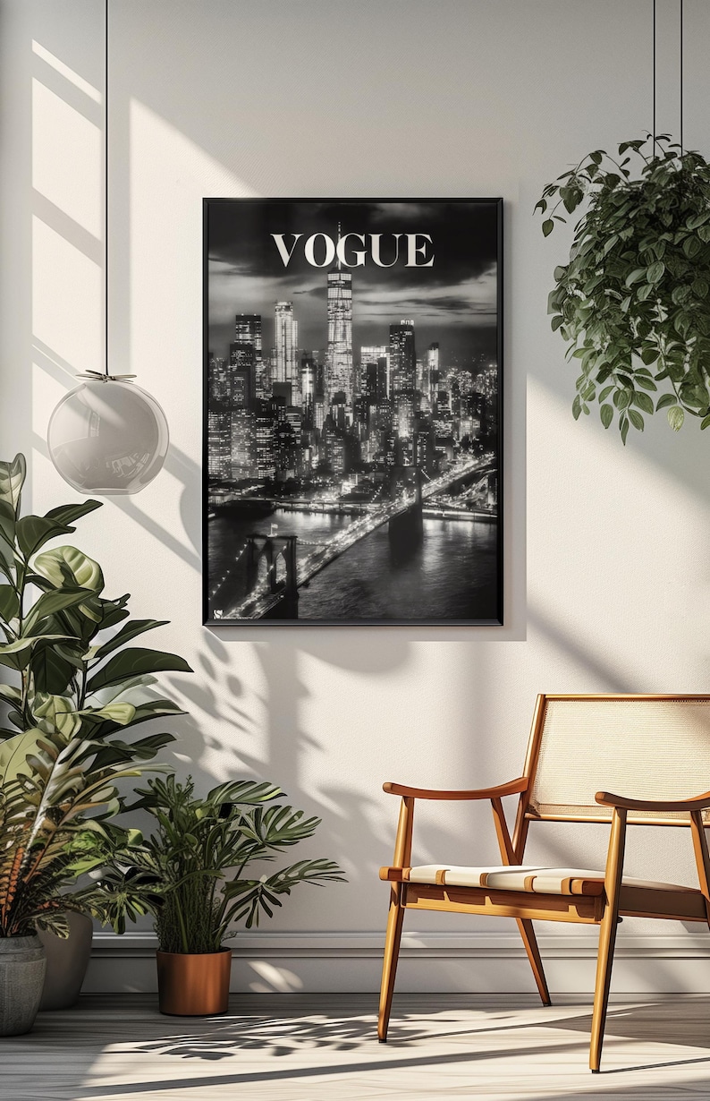 May include: A black and white framed wall art print featuring a nighttime cityscape of New York City with the Brooklyn Bridge in the foreground and the word VOGUE printed in white capital letters at the top center of the rectangular composition.